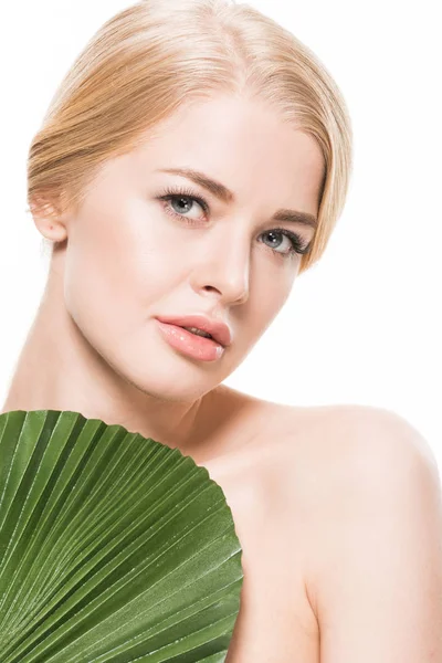 Mulher nua atraente com folha tropical verde no peito olhando para a câmera isolada no branco — Fotografia de Stock