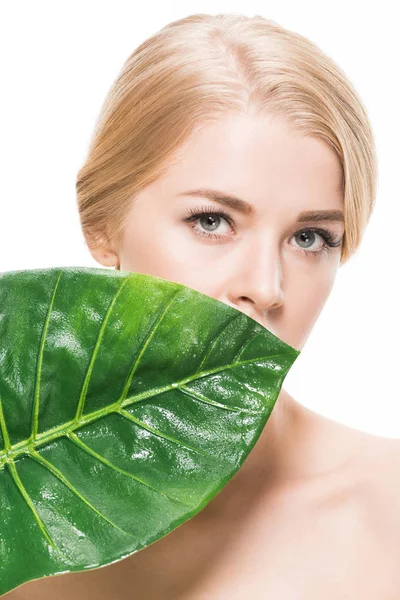 Bela menina nua com folha tropical verde perto do rosto olhando para a câmera isolada no branco — Fotografia de Stock