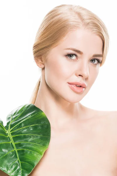 Привлекательная голая девушка с зеленым тропическим листом на плече, смотрящая на камеру, изолированную на белом — стоковое фото