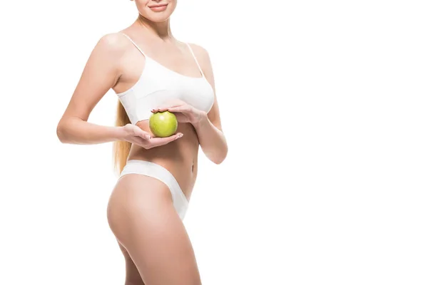 Abgeschnittene Aufnahme eines schönen schlanken Mädchens in weißer Unterwäsche, das Apfel isoliert auf weißer Unterwäsche hält — Stockfoto