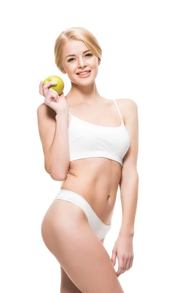 Beautiful young woman in underwear holding green apple and smiling at camera isolated on white — Stock Photo