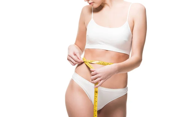 Plan recadré de jeune femme en sous-vêtements mesurant la taille avec du ruban isolant sur blanc — Photo de stock