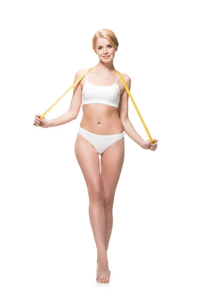 Beautiful slim girl in white underwear holding measuring tape on shoulders and smiling at camera isolated on white — Stock Photo
