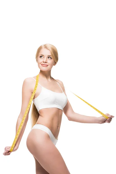 Beautiful smiling slim girl in underwear holding measuring tape and looking away isolated on white — Stock Photo