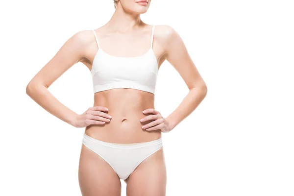 Cropped shot of young slim woman in underwear standing with hands on waist isolated on white — Stock Photo