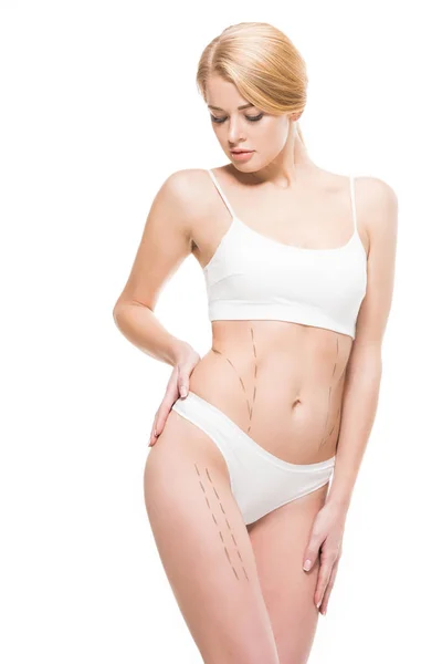 Young woman in white underwear looking at correcting marks on body isolated on white — Stock Photo