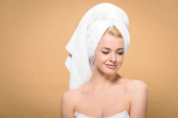 Belle jeune femme souriante avec serviette sur la tête regardant vers le bas isolé sur beige — Photo de stock