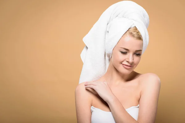 Bella giovane donna sorridente con asciugamano sulla testa che tocca la spalla e guardando giù isolato sul beige — Foto stock