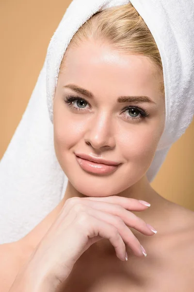 Belle jeune femme avec serviette sur la tête tenant la main sur le menton et souriant à la caméra isolé sur beige — Photo de stock