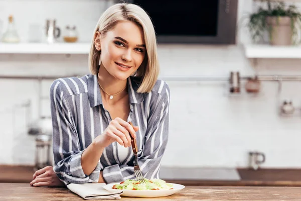 Enfoque selectivo de mujer atractiva comiendo almuerzo y mirando a la cámara - foto de stock