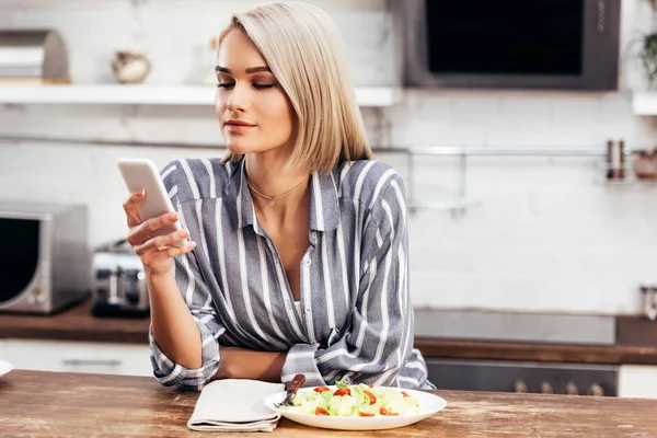 Foyer sélectif de femme attrayante manger et regarder smartphone — Photo de stock