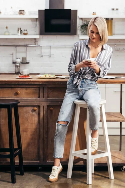 Attraktive Frau auf Stuhl sitzend und Smartphone in der Hand — Stockfoto