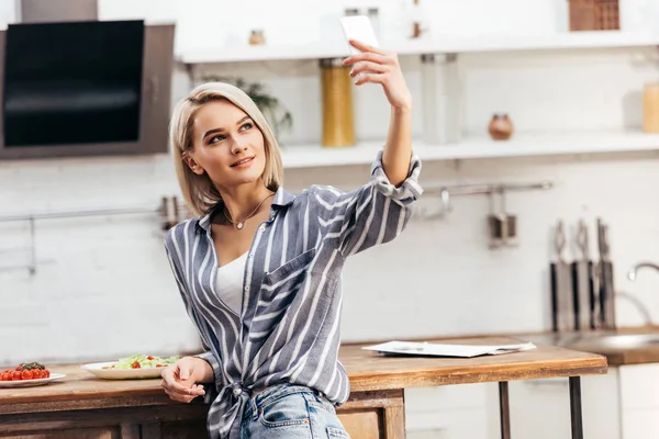 Attraktive Frau macht Selfie am Tisch in der Küche — Stockfoto
