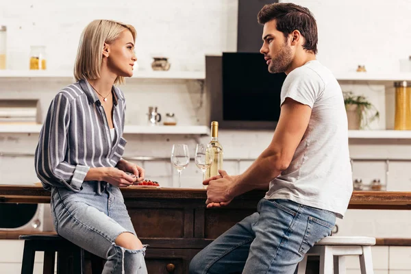 Attractive girlfriend talking to handsome boyfriend in kitchen — Stock Photo