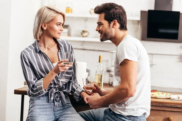 Handsome boyfriend and girlfriend holding wine glasses and hands — Stock Photo