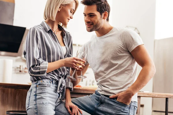 Guapo novio poniendo mano en bolsillo y novia sosteniendo copas de vino - foto de stock