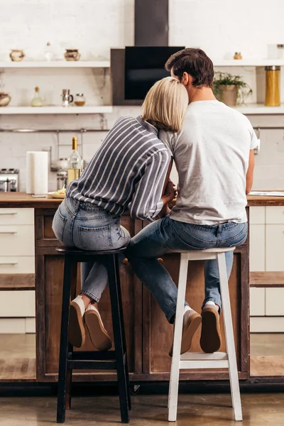 Novio y novia atractiva sentado en sillas en la cocina - foto de stock