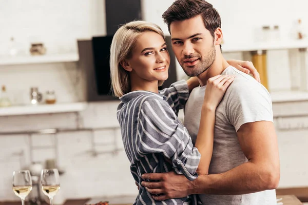 Selective focus of handsome boyfriend and attractive girlfriend hugging looking at camera — Stock Photo