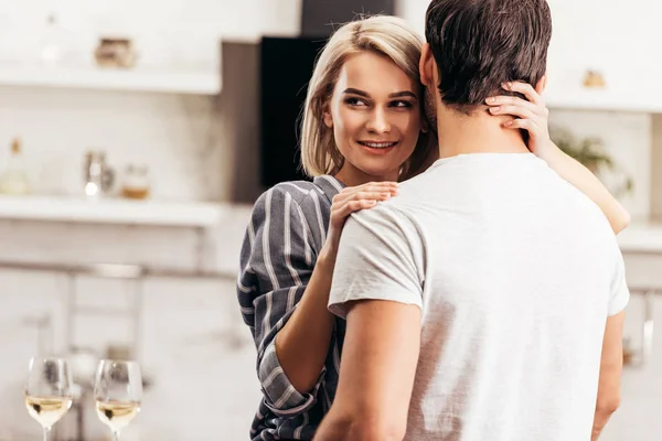 Messa a fuoco selettiva del fidanzato e fidanzata attraente che abbraccia e sorride in cucina — Foto stock