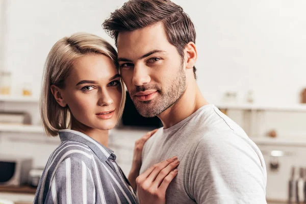 Selective focus of handsome boyfriend and attractive girlfriend hugging and looking at camera — Stock Photo