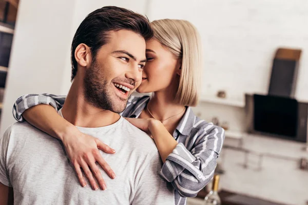 Enfoque selectivo de novio guapo y novia atractiva abrazándose en la cocina - foto de stock