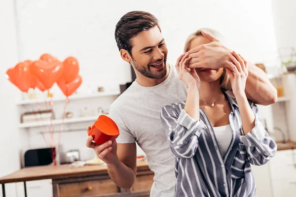 Selektiver Fokus eines hübschen Freundes, der seiner attraktiven Freundin am Valentinstag ein Geschenk macht — Stockfoto