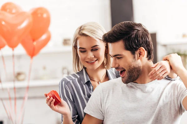 Selective focus of  attractive girlfriend hugging and giving gift to handsome boyfriend on Valentine's day — Stock Photo