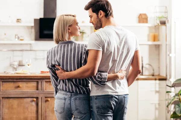 Foco seletivo de namorado bonito e namorada atraente abraçando e de pé na cozinha — Fotografia de Stock