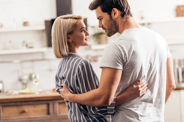 Enfoque selectivo de novio guapo y novia atractiva abrazo y de pie en la cocina — Stock Photo