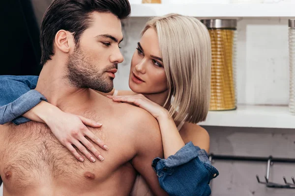 Selective focus of attractive girlfriend and handsome boyfriend hugging at kitchen — Stock Photo