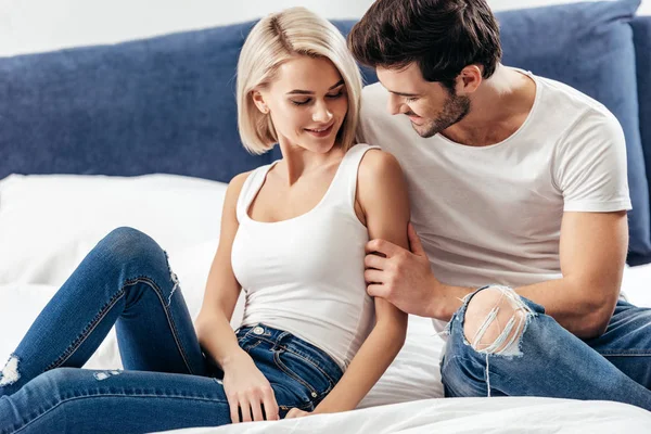 Attractive girlfriend and handsome boyfriend sitting on bed — Stock Photo