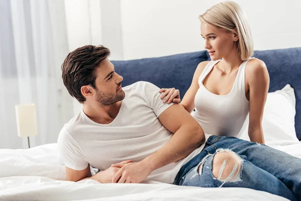 Selektiver Fokus der attraktiven Freundin und des hübschen Freundes, die auf dem Bett sitzen — Stockfoto