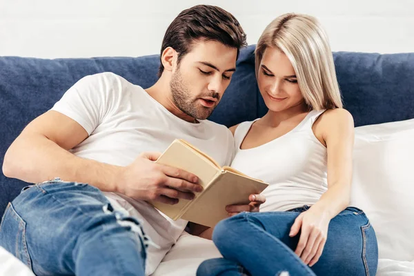 Selective focus of attractive girlfriend and handsome boyfriend reading book — Stock Photo