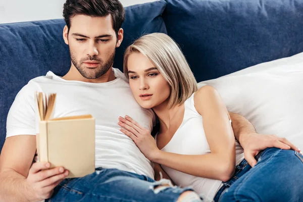 Selective focus of attractive girlfriend and handsome boyfriend laying and reading book — Stock Photo