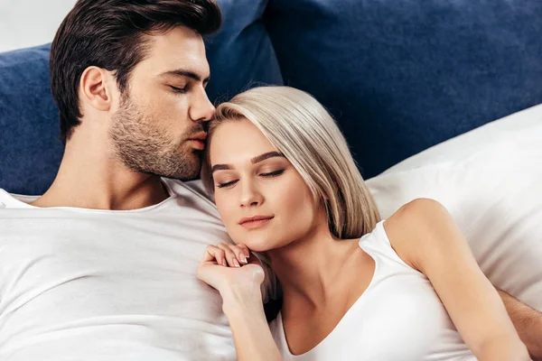 Selektiver Fokus der attraktiven Freundin und des hübschen Freundes beim Küssen und Liegen im Bett — Stockfoto