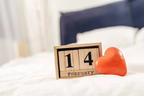 Enfoque selectivo de calendario de madera con 14 letras de febrero y juguete corazón rojo en el día de San Valentín - foto de stock