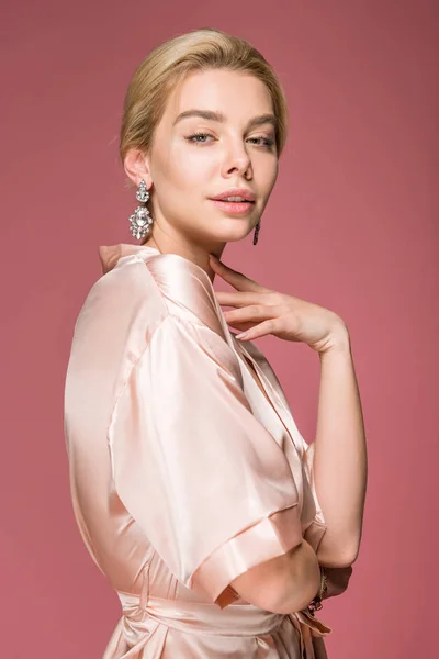 Красива блондинка позує в шовковому халаті, ізольована на рожевому — стокове фото