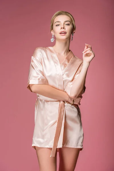 Привлекательная молодая женщина, позирующая в шелковом халате, изолированная на розовом — стоковое фото