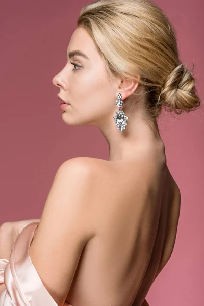 Jolie fille élégante posant dans des boucles d'oreilles et robe de soie, isolé sur rose — Photo de stock