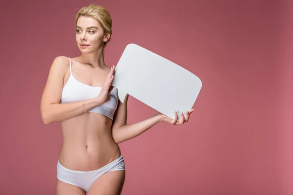 Bela mulher loira em roupa interior branca posando com bolha de fala vazia, isolado em rosa — Fotografia de Stock