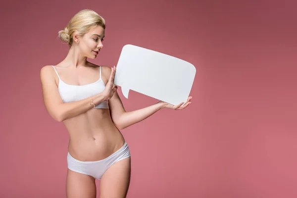 Happy young woman in white underwear posing with empty speech bubble, isolated on pink — Stock Photo