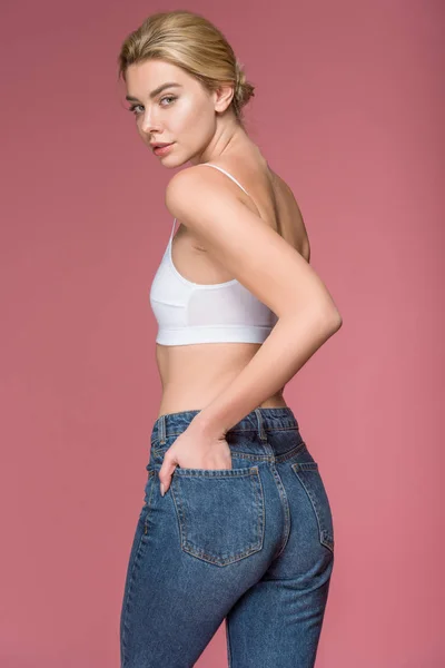Mulher loira atraente posando em jeans e sutiã branco, isolado em rosa — Fotografia de Stock