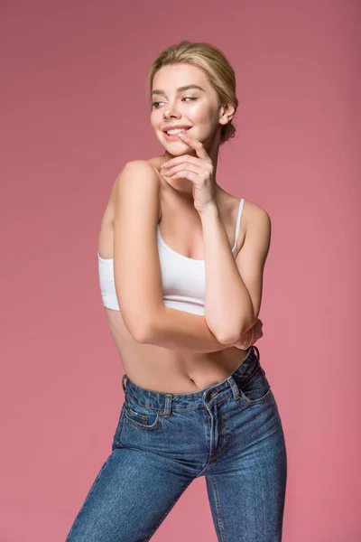 Smiling woman posing in jeans and white bra, isolated on pink — Stock Photo