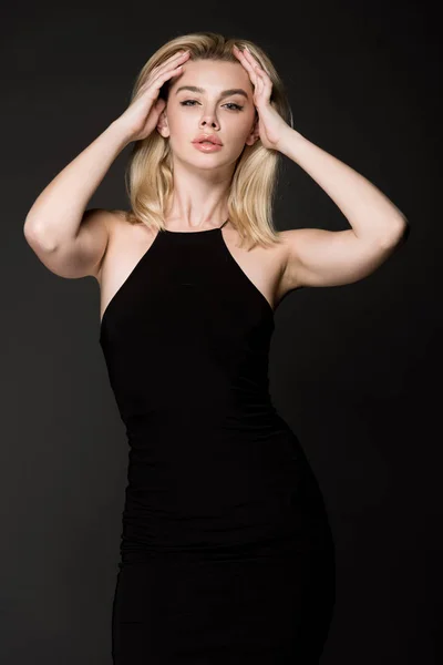 Atractiva chica rubia en vestido negro posando aislado en negro - foto de stock