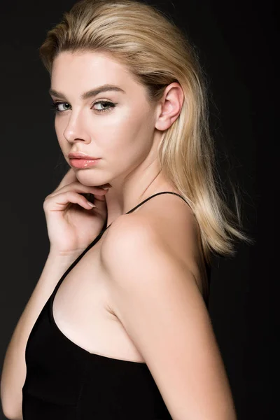 Elegant blonde girl in black dress posing isolated on black — Stock Photo