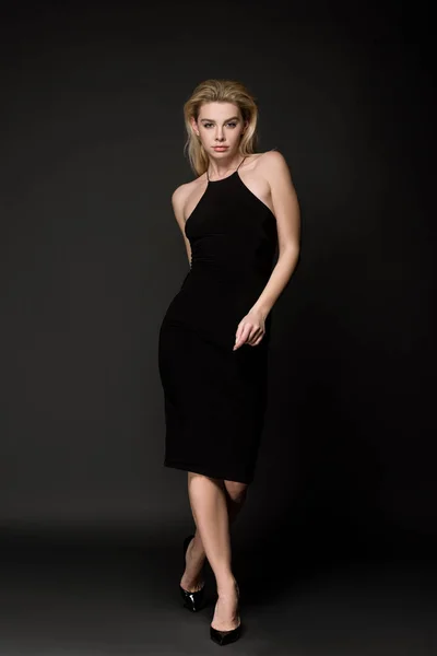 Atractiva chica elegante en vestido negro posando en negro - foto de stock