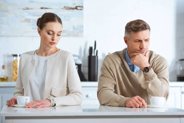Selective focus of adult man ignoring upset woman during breakfast in morning — Stock Photo