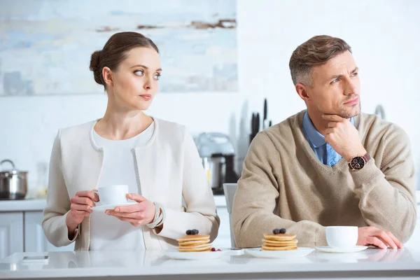 Selective focus of adult man ignoring sad woman during breakfast in morning — Stock Photo