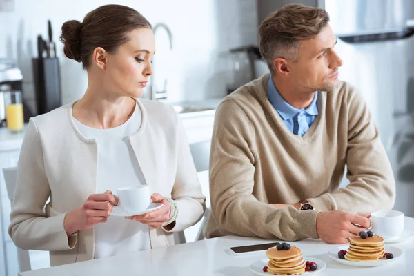 Selective focus of adult man ignoring sad woman during breakfast in morning — Stock Photo