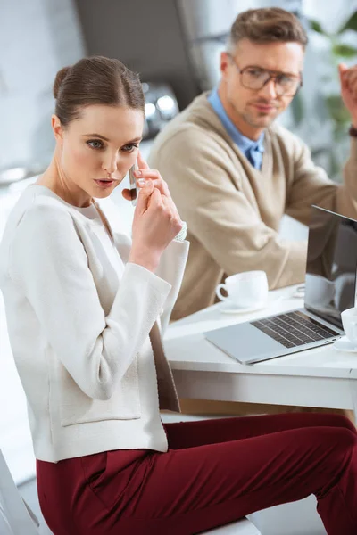 Dissatisfied man looking at woman secretly talking on smartphone during breakfast — Stock Photo